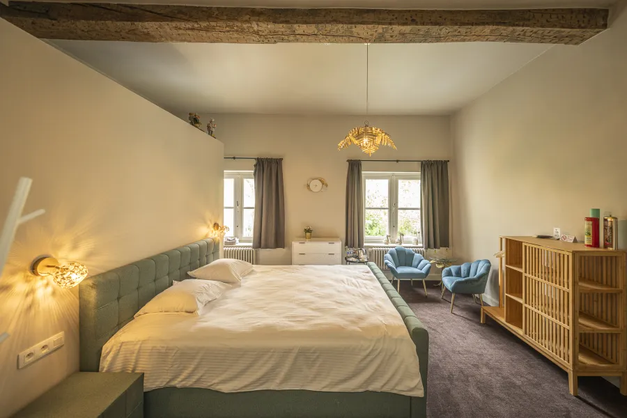 Standard Room confortable avec poutre en bois et fauteuils bleus